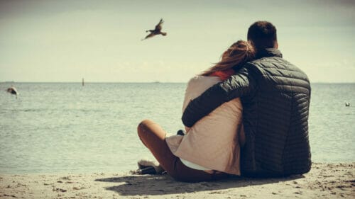 Engaged couple sitting on a beach